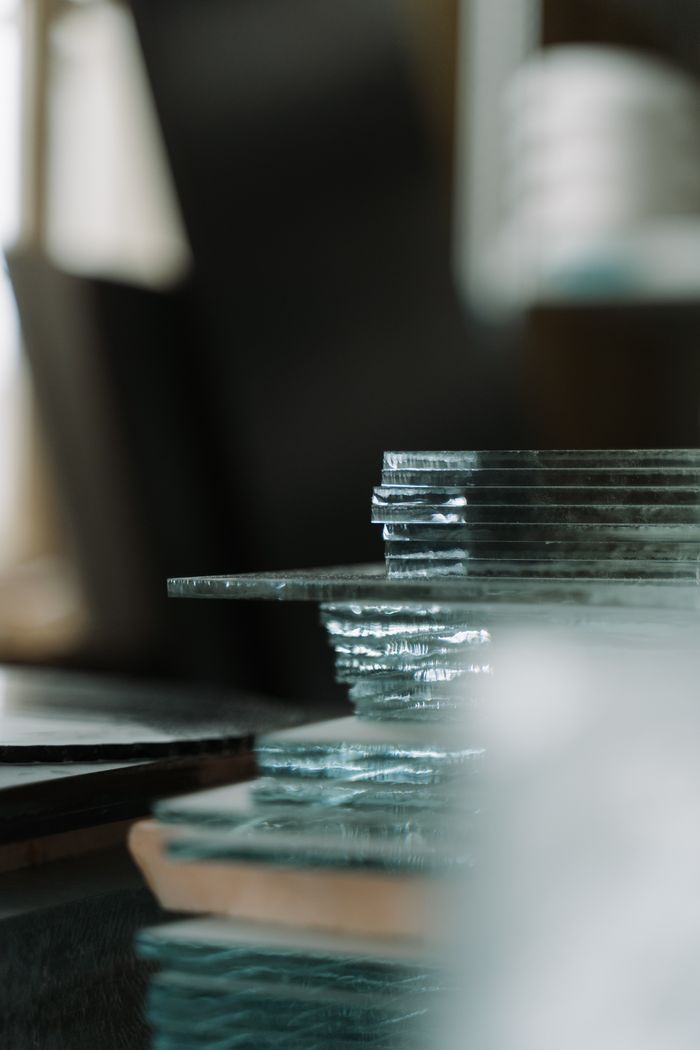A close-up view of stacked glass sheets indoors, capturing textures and reflections.